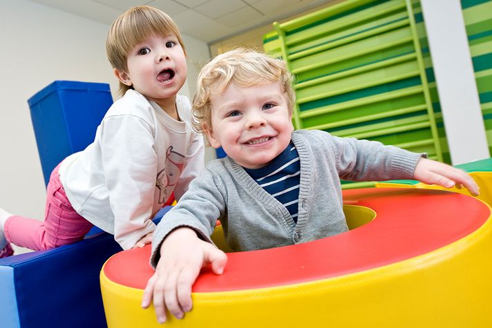 Zwei glückliche Kinder im Alter von 2 Jahren toben in einer Turnecke.