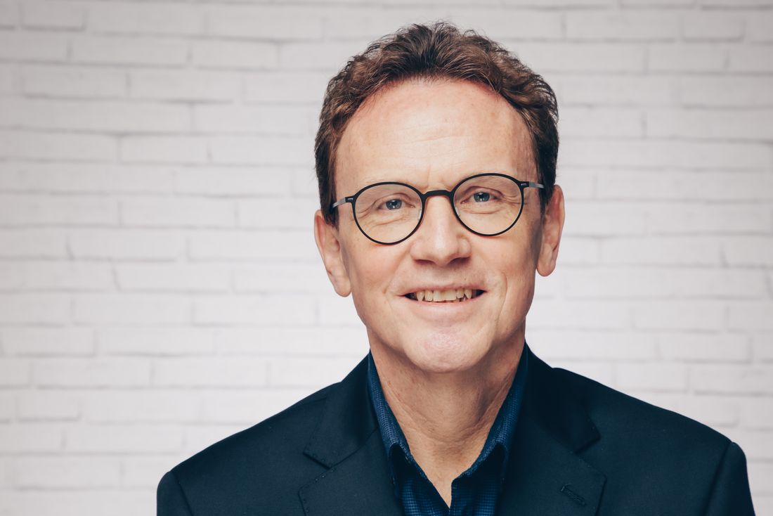 Portrait des Pfarrers Peter Krogull. Ein Mann mit kurzen braunen Haaren und Brille lächelt empathisch in die Kamera.